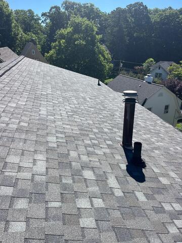 Clean, newly installed gray shingle roof with vents after roofing work