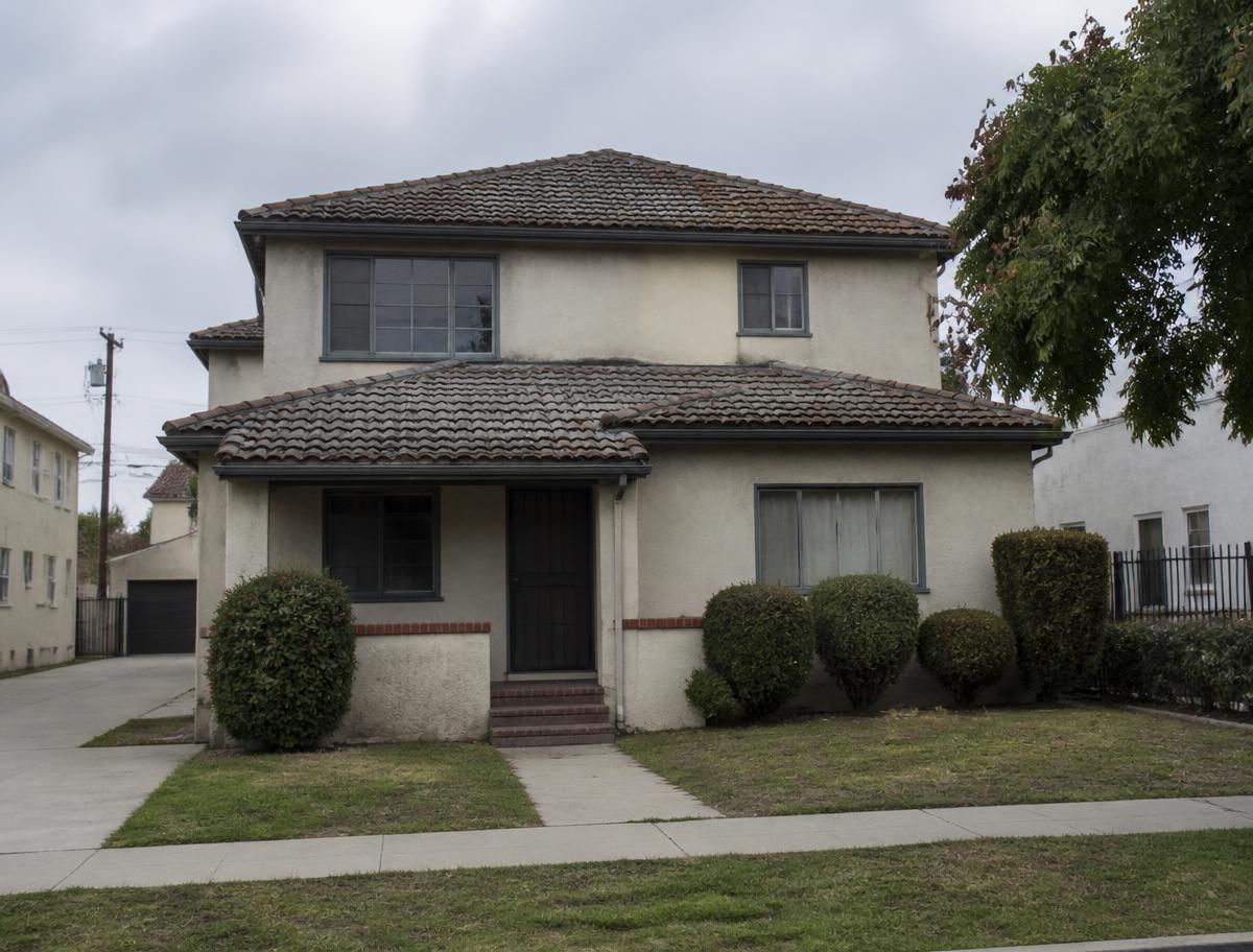 Two-story home with a faded, stained roof before roofing work